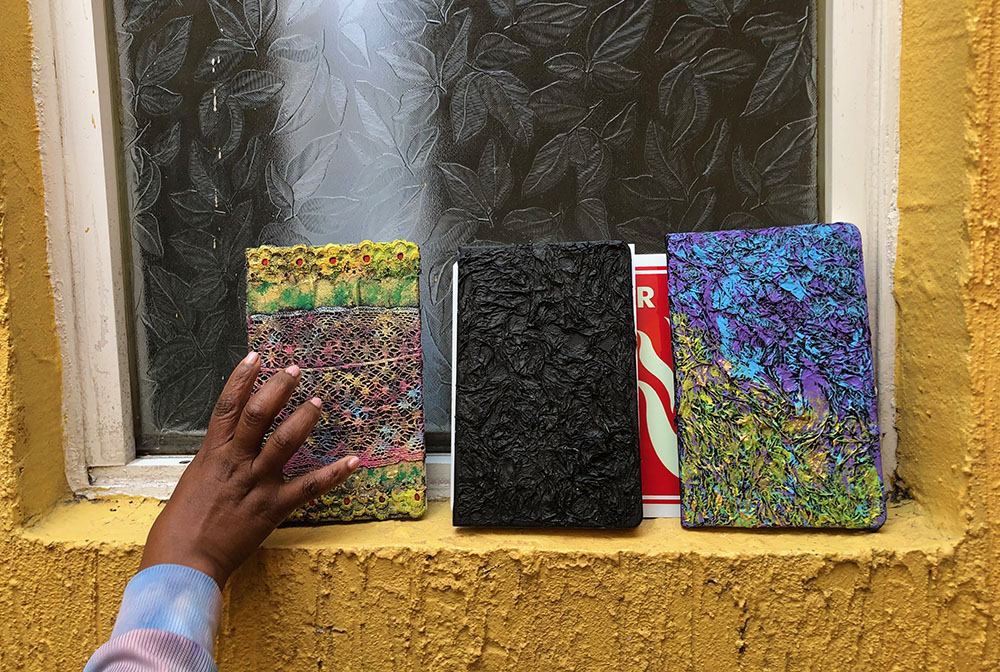 One of the women reaches for a book she decorated using the techniques she learned at Casa Madre Antonia with basic materials: crumpled tissue paper, lace and paint. (GSR photo/Tracy Barnett)