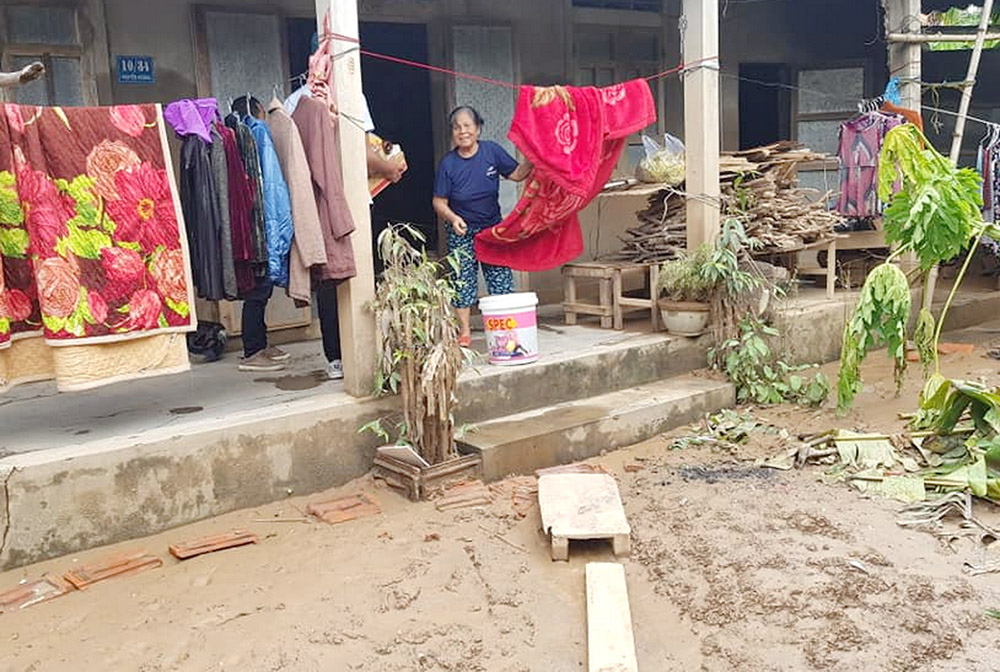 Le Thi Mung dries blankets and clothes in front of her house after floods in Mai Duong village, Vietnam, Oct. 5. (GSR photo/Joachim Pham)