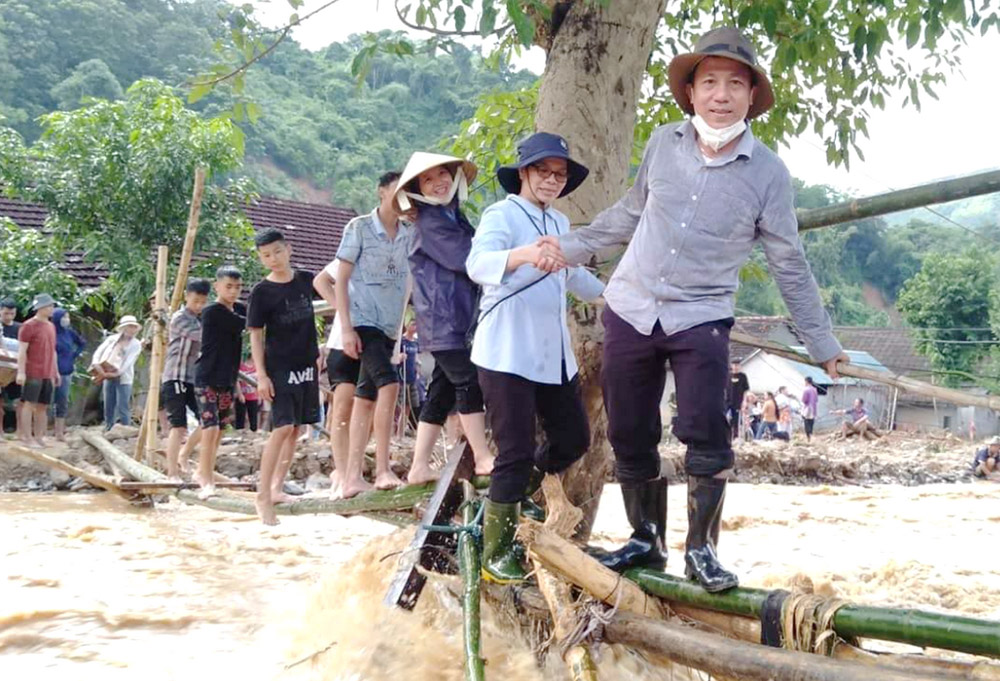 Lovers of the Holy Cross of Vinh Sr. Josephine Hoang Thi Lan (second from front) leads other sisters and people to step on a footbridge over a stream to visit Son Ha village in Nghe An province, Vietnam, Oct. 5. (Courtesy of Josephine Hoang Thi Lan)