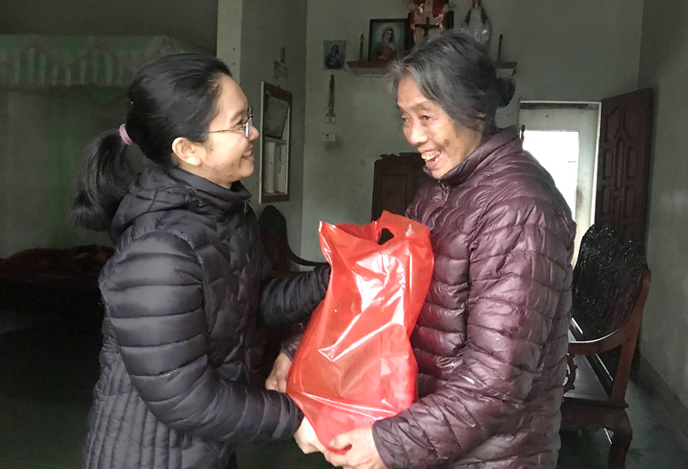 Daughters of Our Lady of the Visitation Sr. Agnes Le Thi Thanh (left) offers gifts to a woman at Van Quat village in Thua Thien Hue province, Vietnam, Oct. 22. (GSR photo/Joachim Pham)