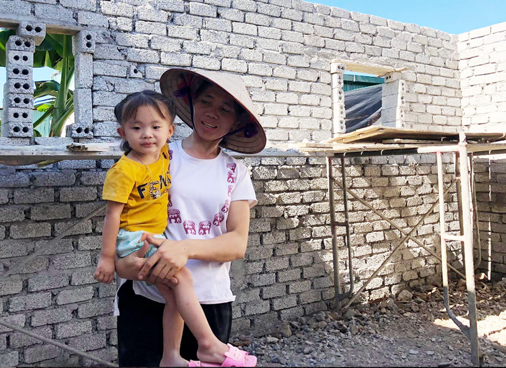 Lucia Nguyen Thi Tam Nguyen holds her granddaughter in her unfinished house in Thua Thien Hue province, Vietnam, Nov. 2. (GSR photo/Joachim Pham)