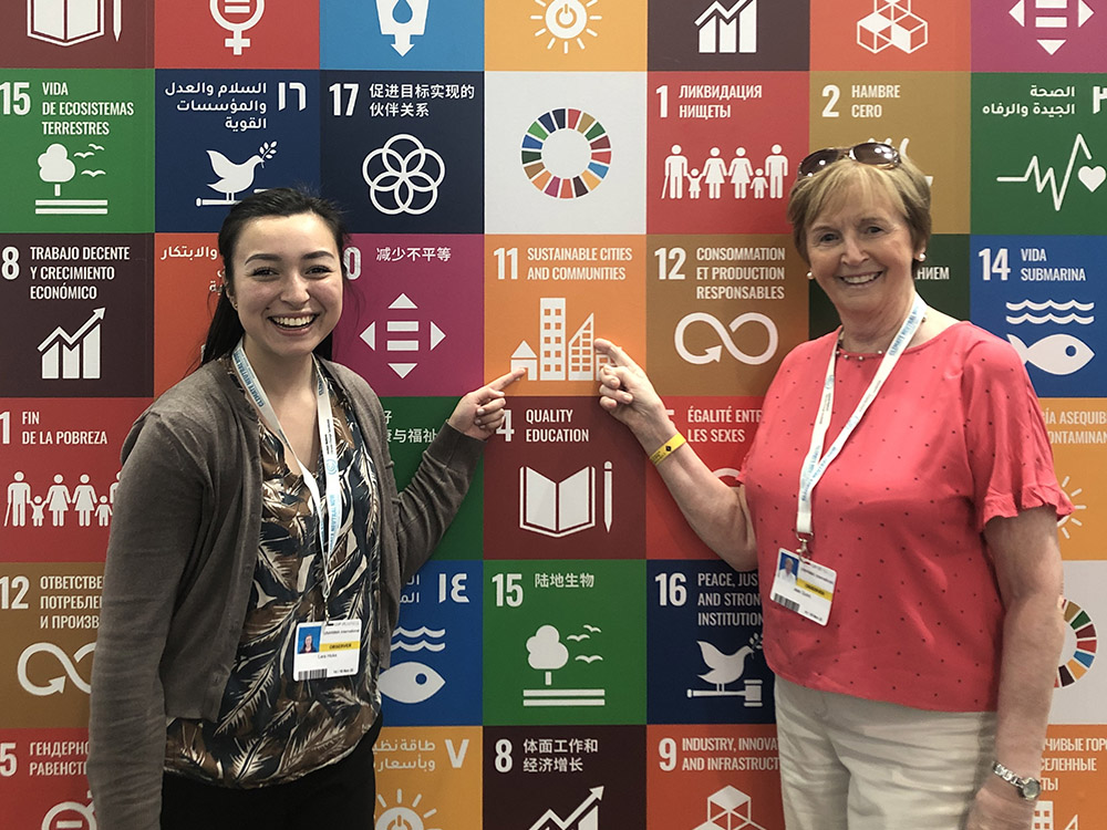 UNANIMA International executive assistant Lara Hicks, left, and Daughter of Wisdom Sr. Jean Quinn stand in front of an illustration of the U.N. Sustainable Development Goals at the COP27 climate summit in November in Sharm el-Sheikh, Egypt. (Courtesy of Jean Quinn)