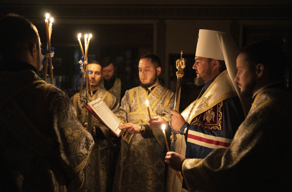 Metropolitan Oleksandr delivers a religious service with clerics inside the Transfiguration of Jesus Orthodox Cathedral during blackout caused by recent Russian rocket attacks, in Kyiv, Ukraine, Saturday, Dec. 3, 2022. (AP Photo/Efrem Lukatsky)