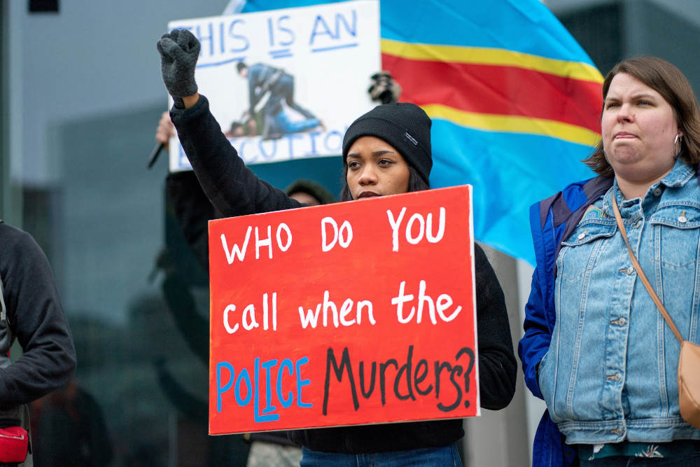 Demonstrators in Grand Rapids, Michigan, hold signs April 15 protesting the April 4 fatal shooting by a police officer of Patrick Lyoya, an unarmed Black man, during a traffic stop. (CNS/Reuters/David Delgado)