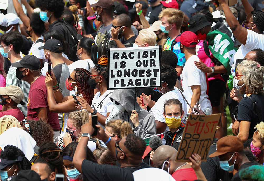 Protesters in Washington stand with a sign reading "Racism is Our Longest Plague" Aug. 28, 2020, at the spot where civil rights leader the Rev. Martin Luther King Jr. delivered his "I Have a Dream" speech. (CNS/Reuters/Tom Brenner)