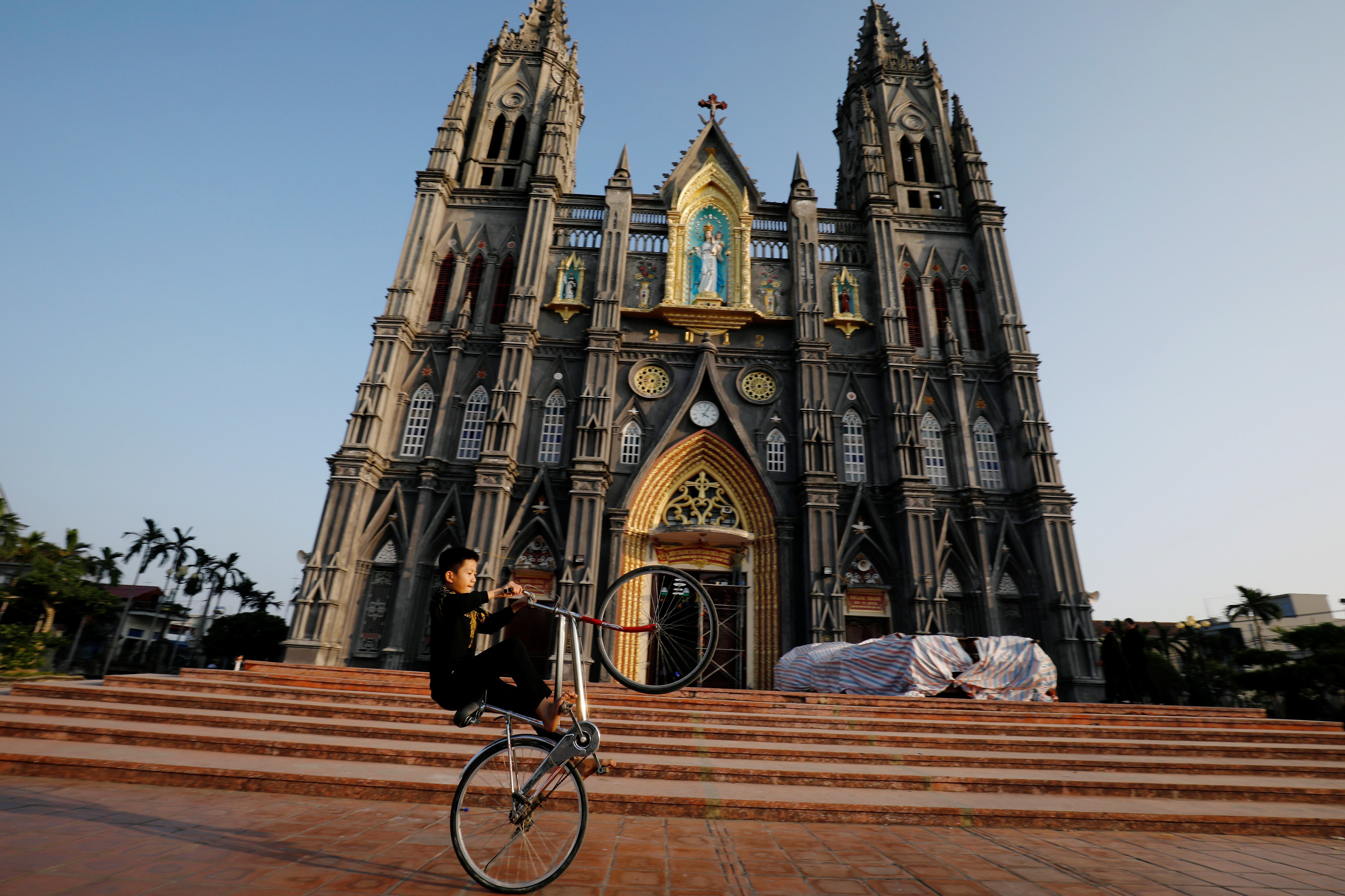 A boy in Nam Dinh, Vietnam, cycles in front of a church Dec. 6, 2020. (CNS photo/Kham, Reuters)
