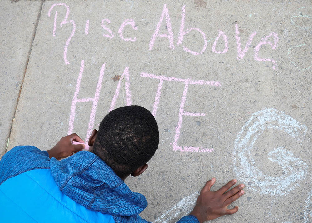 A boy writes a message on a sidewalk May 18 in Buffalo, New York, where a mass shooting took place May 14 at a Tops supermarket. (CNS/Reuters/Brendan McDermid)