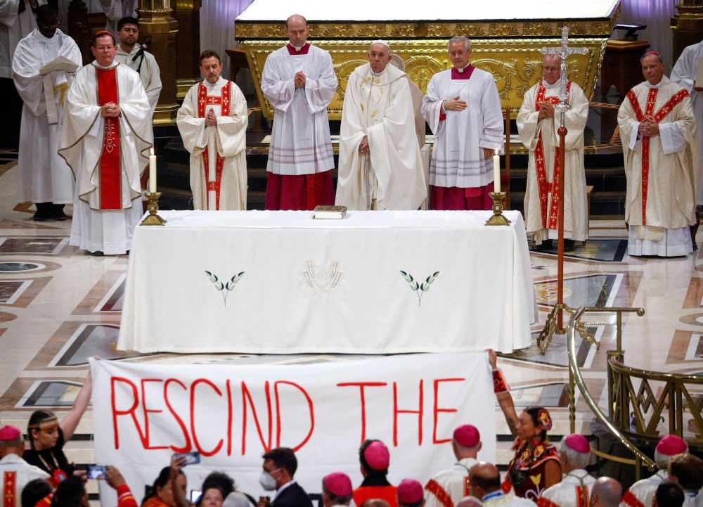 Indigenous people hold a banner calling on Pope Francis to "rescind the doctrine," during a papal Mass at the National Shrine of Sainte-Anne-de-Beaupré in Quebec in this July 28, 2022, file photo. (CNS photo/Guglielmo Mangiapane, Reuters)