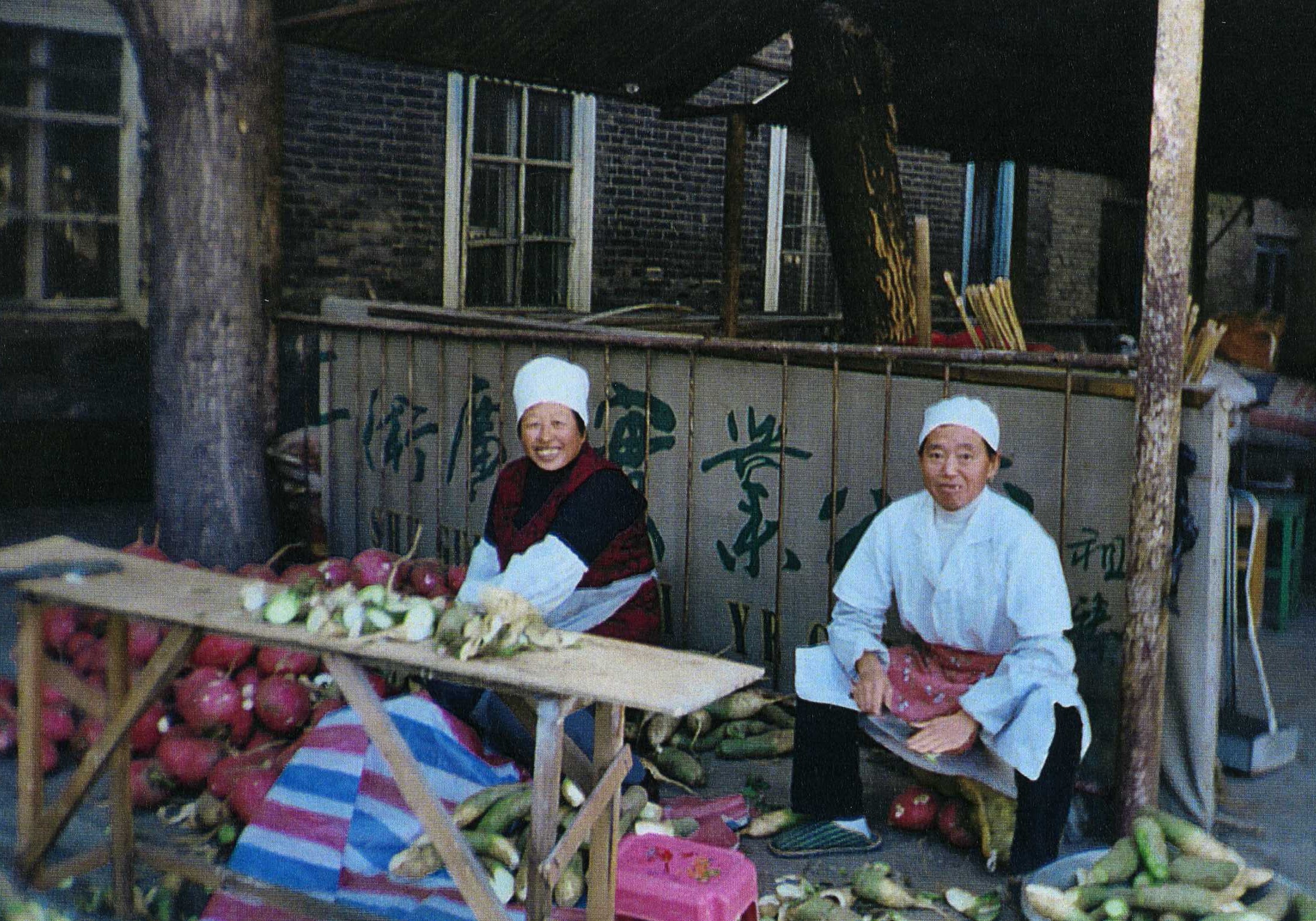 2 sisters sit outside preparing food