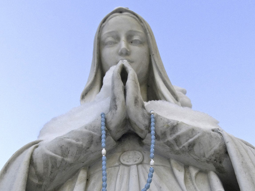 A rosary is draped over the praying hands of a statue of Mary outside the Cathedral of the Immaculate Conception in Syracuse, New York. (CNS/Catholic Sun/Paul Finch)