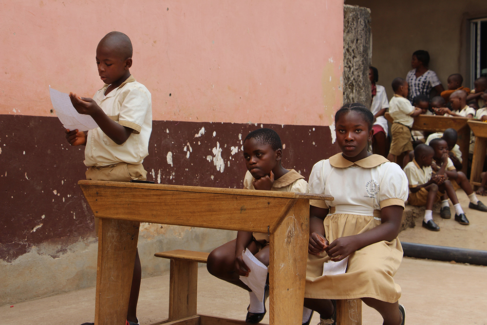 Three Cameroonian children sit at a desk