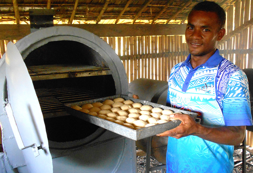 A student places a fresh batch of buns into the oven in October 2021 at San Isidro Care Centre. (Courtesy of Maria Fe Rollo)