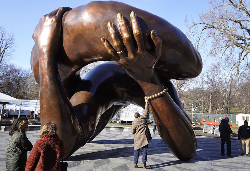 A man reaches to touch a detail of the 20-foot-high bronze sculpture "The Embrace," a memorial to Dr. Martin Luther King Jr. and Coretta Scott King, in the Boston Common Jan. 10 in Boston. The statue was officially unveiled during ceremonies Jan. 13. (AP/Steven Senne)