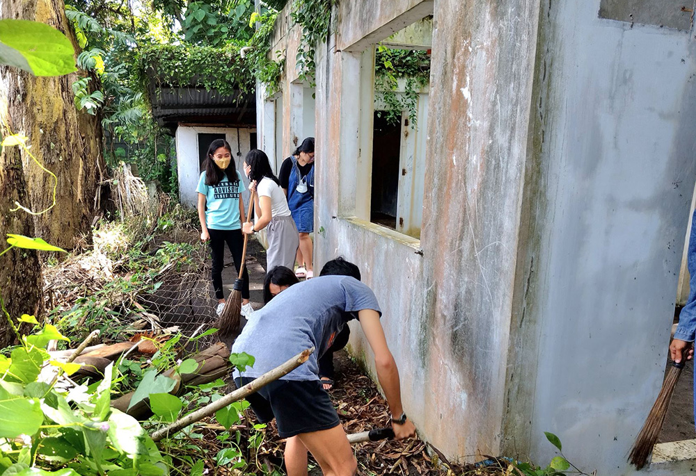 Under the leadership of the Sisters of the Good Samaritan, students collect trash at what remains of the small building of the homeowners' association, in the park they are rehabilitating in the city of Bacolod, in Negros Occidental, in the Philippines. (Courtesy of the Sisters of the Good Samaritan)