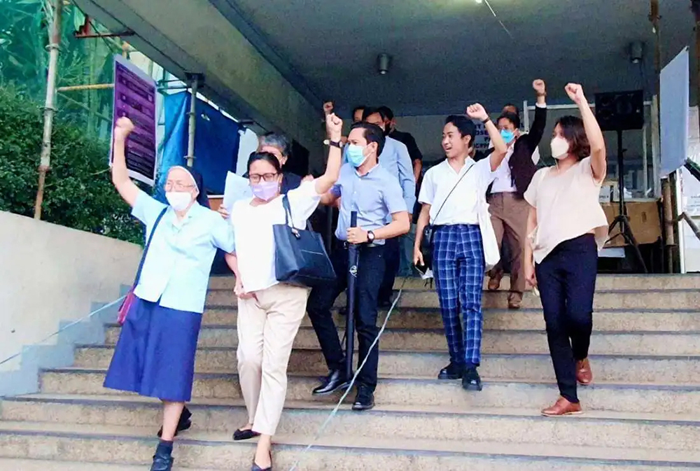 A group of Filipino people with their fists raised stand on steps of a courthouse in Manila
