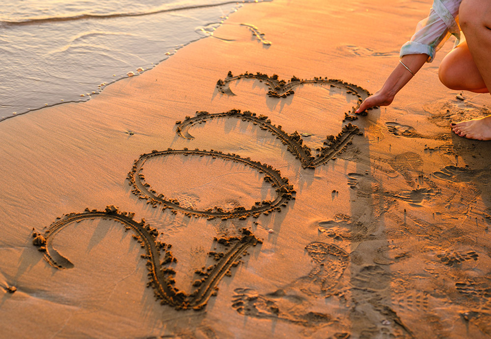 A girl writes 2023 in the sand on a beach (Unsplash/Engin Akyurt)