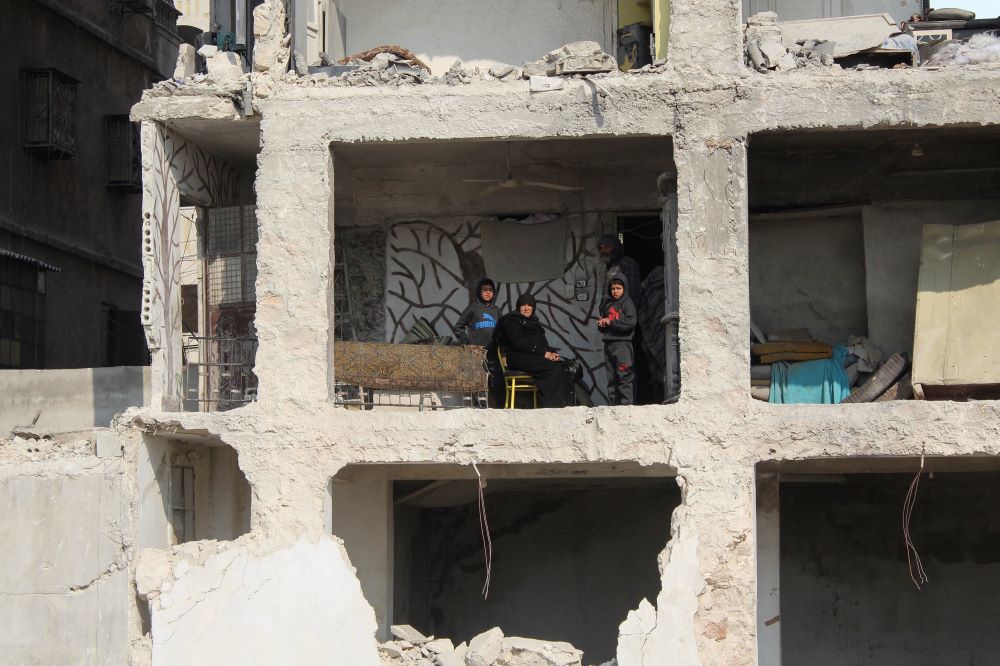 A Syrian earthquake survivor sits with her grandchildren inside the shell of her son's destroyed home in Aleppo Feb.13. (