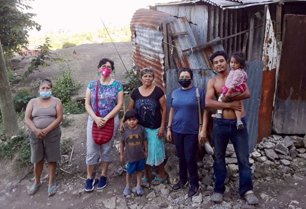 A group of pople stand in front of a shabby building