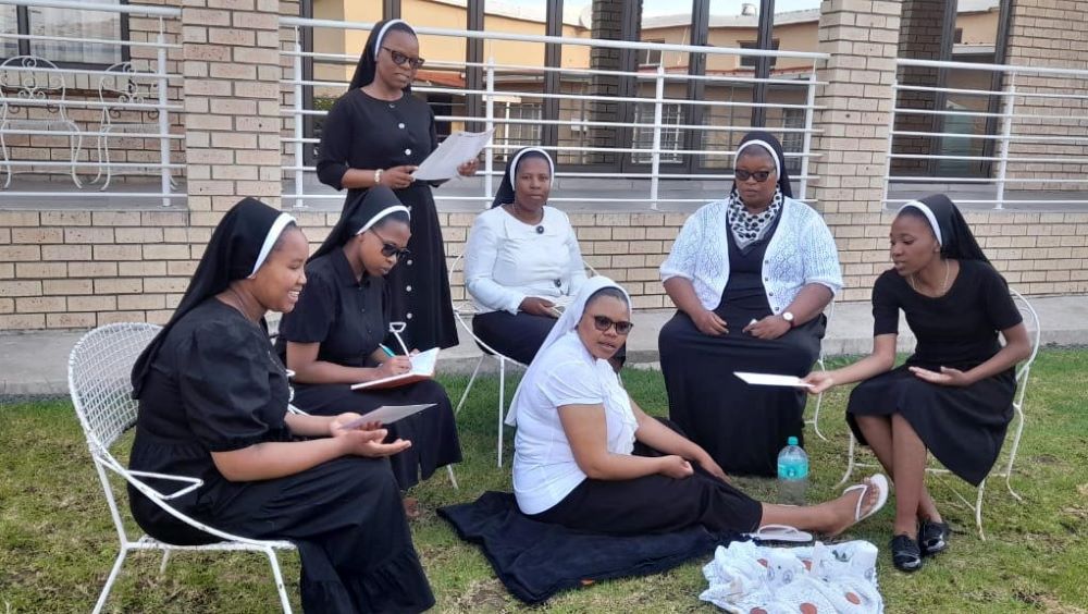 Sisters sit on chair and on grass to pray together