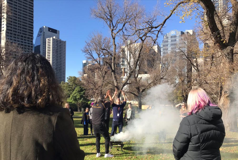 Women watch a healing ceremony that includes smoke.