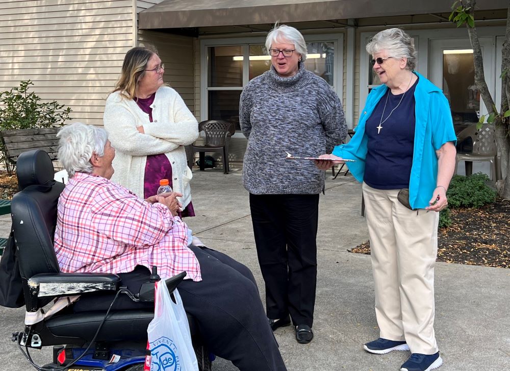 Speers Court Apartments resident Peggy Perkinson (left) and former resident Brenda Scott, both of whom help with activities for the complex residents stand outside the complex in Dayton, Kentucky, in October 2022. With them are Andrea Janovic, an attorney who helps residents with legal matters; and Sr. Francis Margaret Maag (far right). (Courtesy of Francis Margaret Maag)