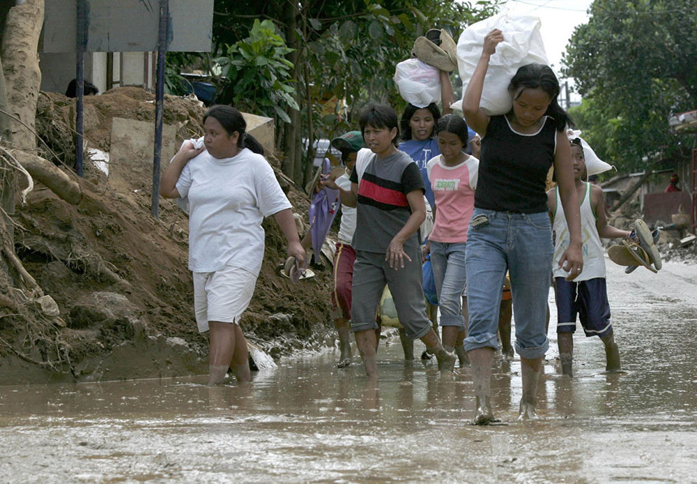 Filipino villagers carry relief goods in Infanta, Philippines, Dec. 20, 2004, following a typhoon and three tropical storms in the span of two weeks that left nearly 1,800 people dead or missing. (CNS/Reuters)