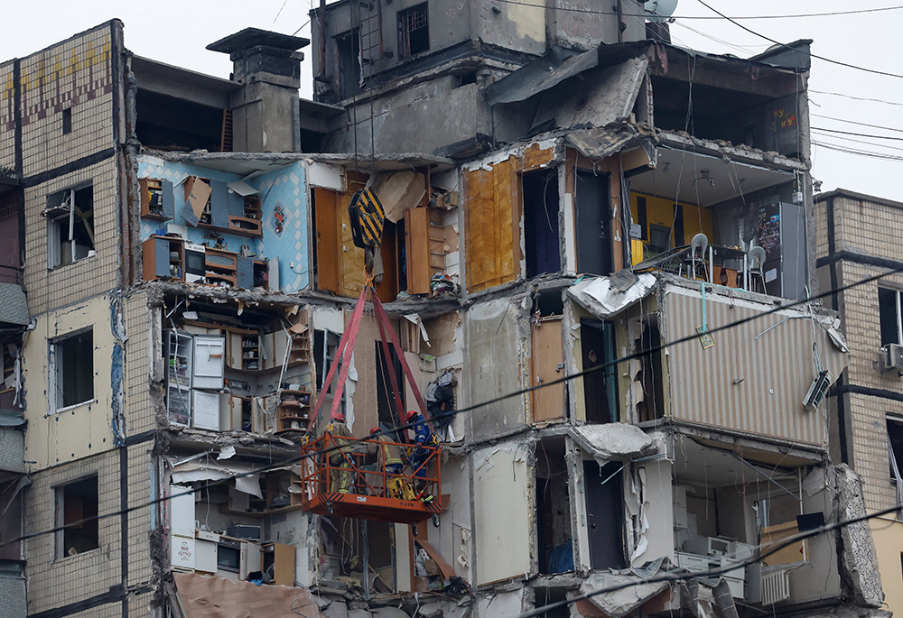 Emergency personnel are seen Jan. 16 working at the site where an apartment block was heavily damaged by a Russian airstrike in Dnipro, Ukraine. At least 30 people were killed in the airstrike, the national emergencies service reported as rescue workers scrambled to reach survivors in the rubble. (OSV News photo/Reuters/Clodagh Kilcoyne)