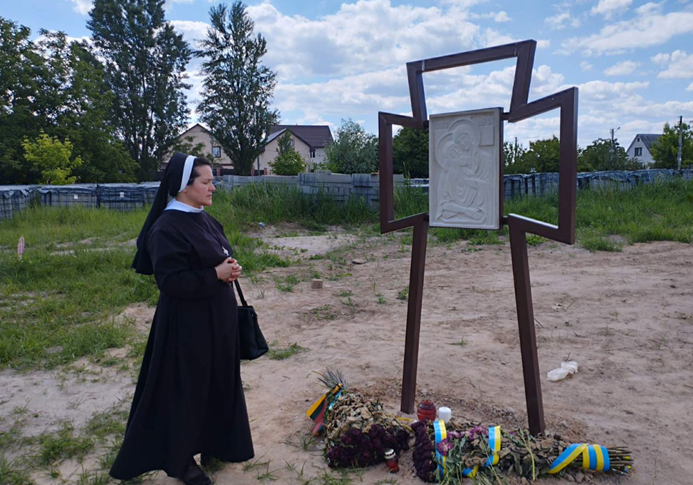 La Hna. Yanuariya Isyk presenta sus respetos ante una fosa común de víctimas civiles de presuntos crímenes de guerra rusos en Bucha (Ucrania), durante una visita en mayo de 2022.