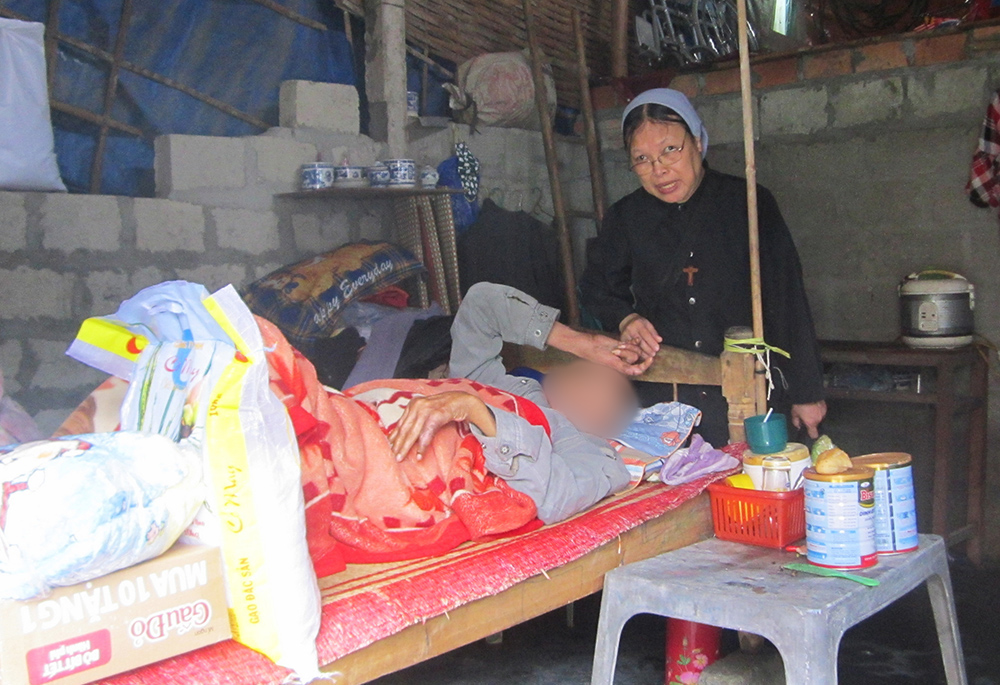 Filles de Marie Immaculée Sr. Lucia Nguyen Thi Ngo offers rice, instant noodles and milk to a patient (whose face is obscured to protect identity) Nov. 12, 2022, in Vietnam's Phu Loc district. (GSR photo/Joachim Pham)