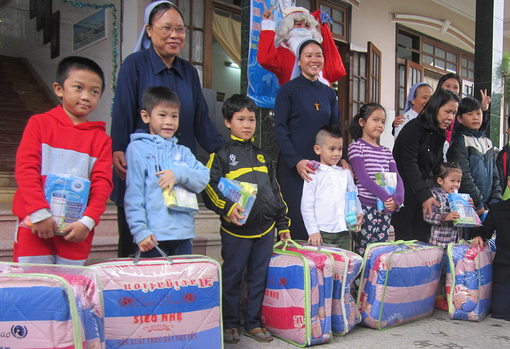 Filles de Marie Immaculée Srs. Lucia Nguyen Thi Ngo (left) and Clare Mai Tran Tu Uyen give blankets and milk to orphans and vulnerable children Dec. 21, 2022, in Hue, Vietnam. (GSR photo/Joachim Pham)