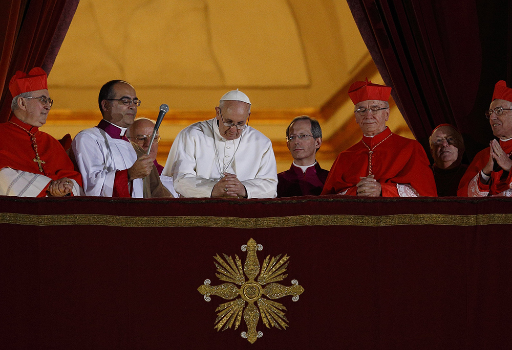 Pope Francis bows his head in prayer during his election night appearance on the central balcony of St. Peter's Basilica March 13, 2013, at the Vatican. The crowd joined the pope in silent prayer after he asked them to pray that God would bless him. (CNS/Paul Haring)
