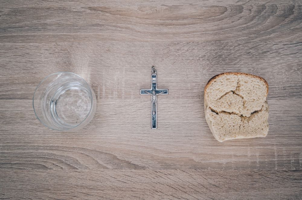 a glass of water, a crucifix and a piece of broken bread on a table