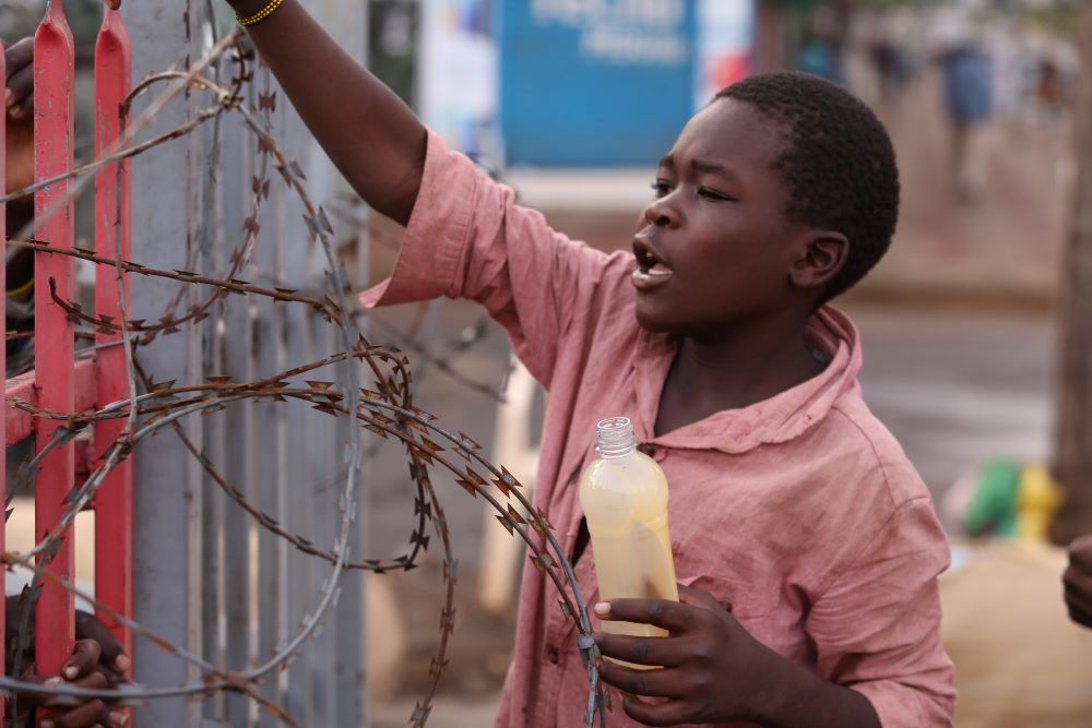 Boy on the street holds bottle with glue.