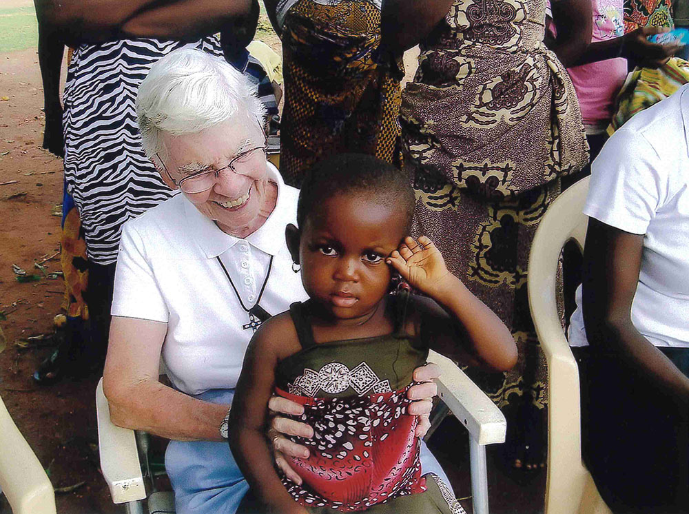 Sr. Kathleen Feeley of the School Sisters of Notre Dame holds a child at a village meeting in a small village near Sunyani, Ghana. (Courtesy of Kathleen Feeley)