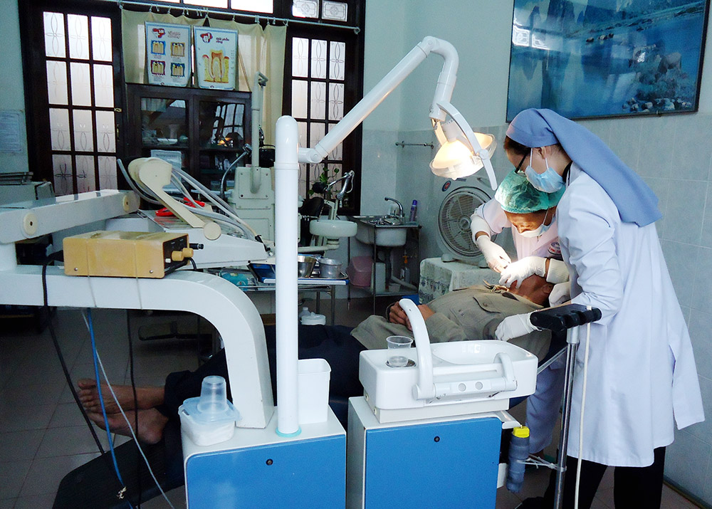 Sr. Mary Elizabeth Truong Thi Ha, a dentist, and another dental surgeon take care of a patient's teeth at the Kim Long Charity Clinic in Hue, Vietnam, on Dec. 2, 2022. (Joachim Pham)
