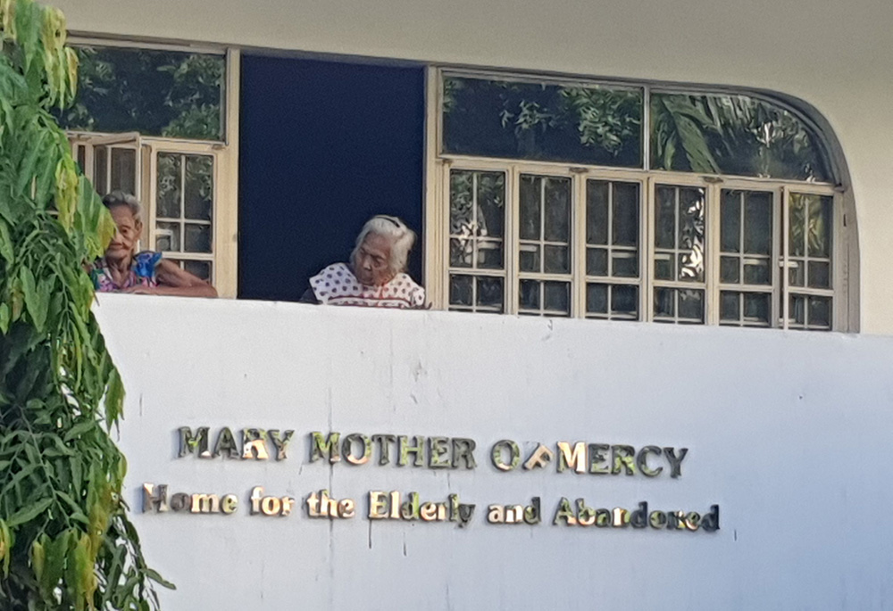 Two residents of Mary Mother of Mercy Home for the Elderly and Abandoned spend afternoon time outside on the second floor of their home. (Oliver Samson)