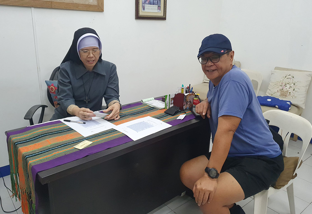 Sr. Venus Marie S. Pegar, vocation director of the Sisters of St. Francis Xavier's community in the Philippines, meets with Ramon Torres, a retired pilot, on a fundraising initiative by his granddaughter and her high school classmates for the abandoned women. (Oliver Samson)