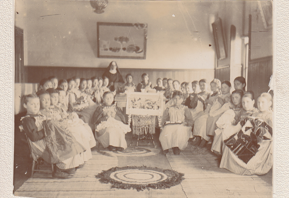 Female students show their handiwork at St. Benedict's Mission School on the White Earth Indian Reservation in Minnesota in the 1890s. ("Work room at St. Benedict's Mission School," College of Saint Benedict/Saint John's University Libraries, https://csbsjulib.omeka.net/items/show/928)
