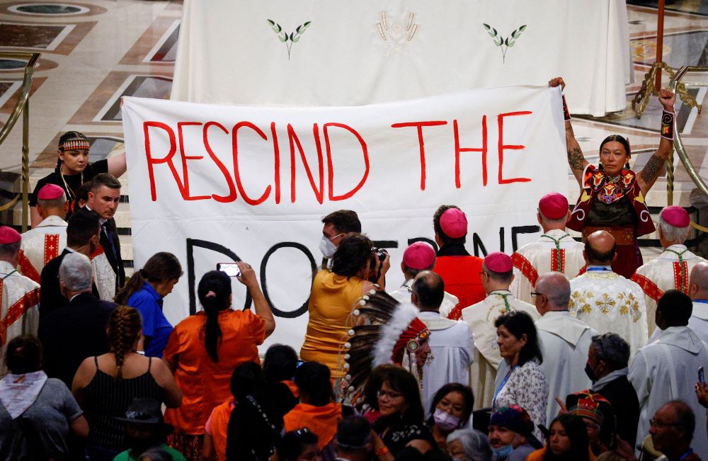 Indigenous people hold a banner calling on Pope Francis to "rescind the doctrine," a reference to the so-called Doctrine of Discovery, during a papal Mass in Quebec.