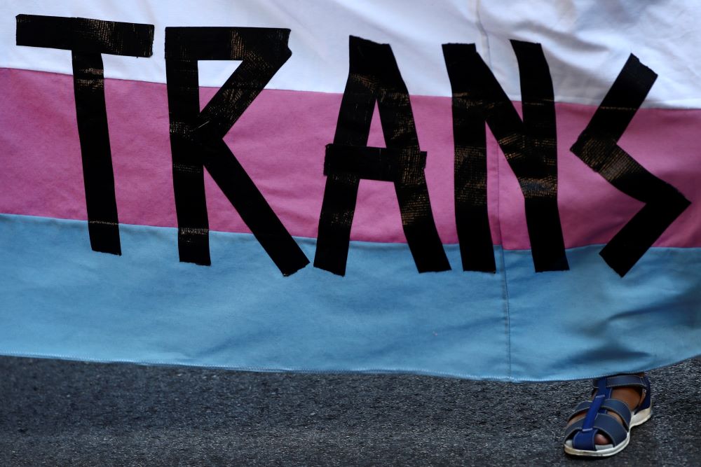 A person holds a "Trans" banner