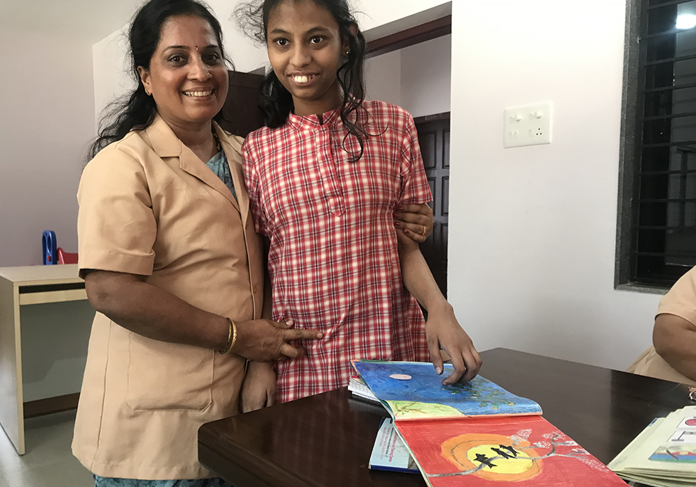Rolene Stuthi Kunder, a student of the autism center, poses with her teacher Shailaja Poojari as she showed her paintings. (Thomas Scaria)