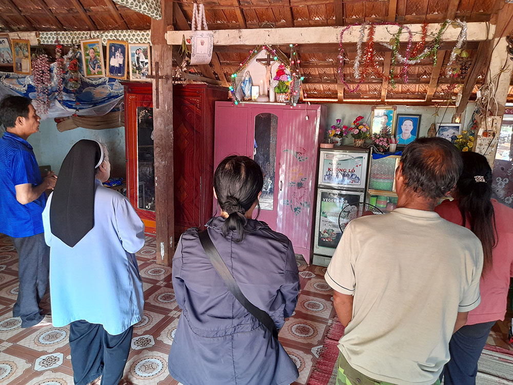 Mary Queen of Peace Sr. Teresa Nguyen Thi Bich and another sister (in black) join Ede ethnic family members in praying at their house while visiting them in Dak Lak province in Vietnam. The nuns encourage them to work hard to support themselves and invite their neighbors to visit the church as a way to introduce them to Catholicism. (Joachim Pham)