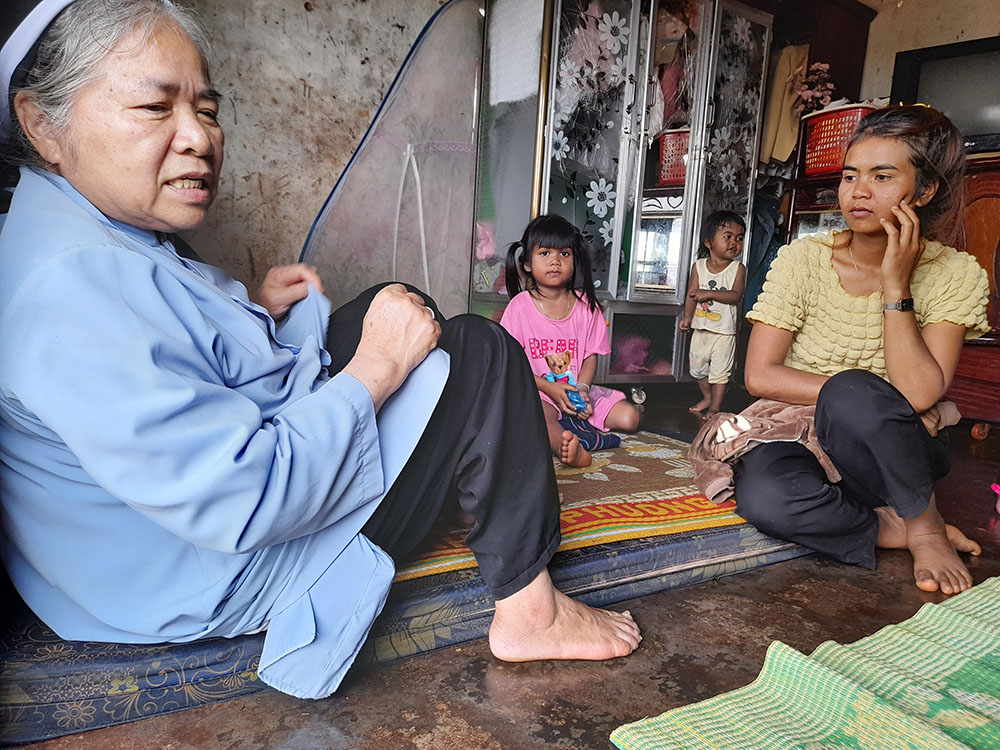 Mary Queen of Peace Sr. Teresa Nguyen Thi Bich, who's in her 70s, meets Sara, an Ede mother who has three children in Dak Lak province in Vietnam. She and her husband have no land and collect other people's peppercorns in the neighboring province of Dak Nong to put food on the table. Without money to send their kids to school, they let their children play under trees while they work. (Joachim Pham)