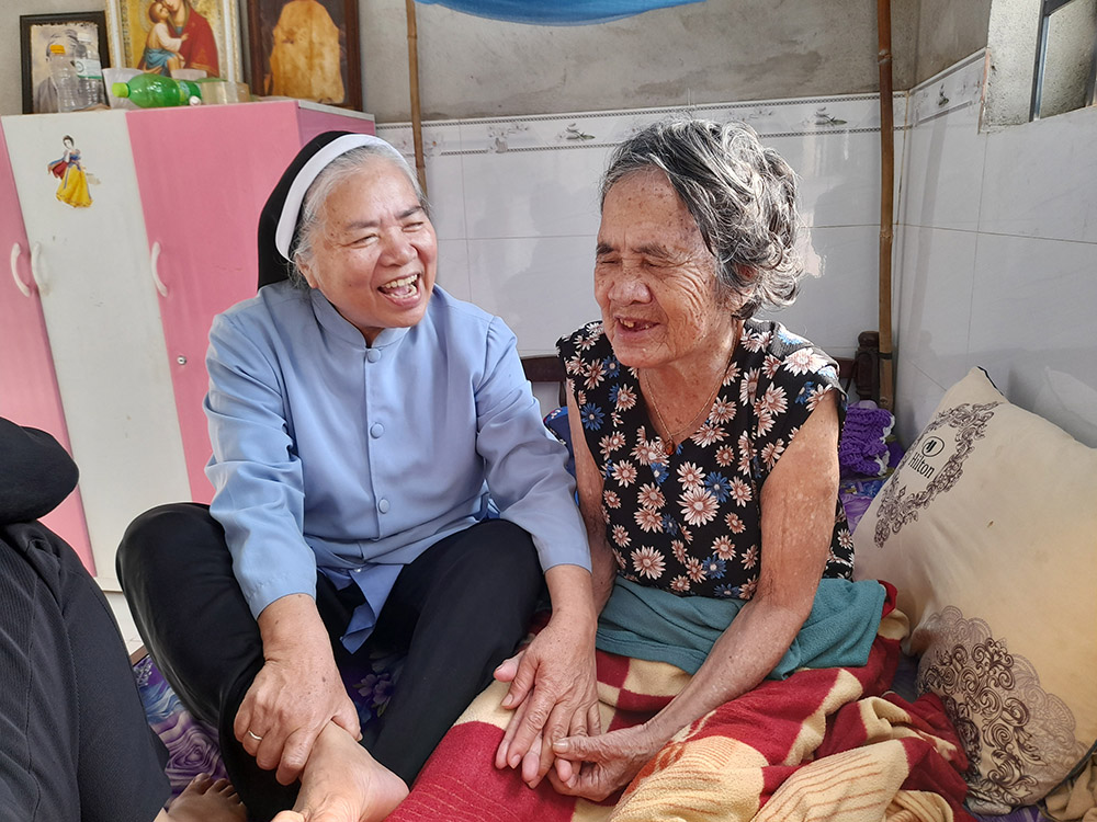 Mary Queen of Peace Sr. Teresa Nguyen Thi Bich talks excitedly with Anna H'roi, who is in poor health and is looked after by her children in Dak Lak province, Vietnam. One of her nine children is a priest who serves Ban Me Thuot Diocese. (Joachim Pham)