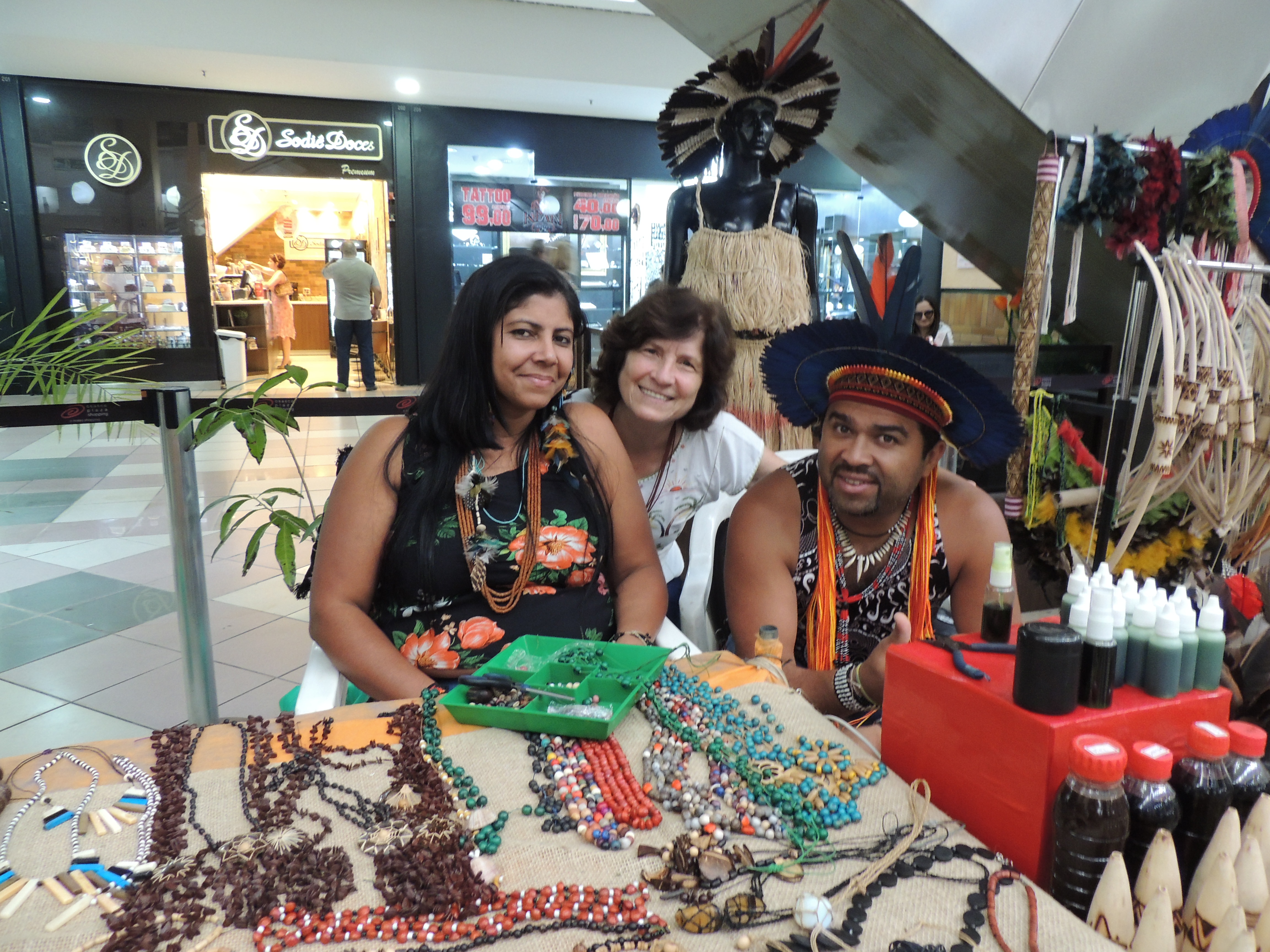 Two Pankararu Indians sitting at a stall in a shopping mall with Sr. Lucia Gianesini 