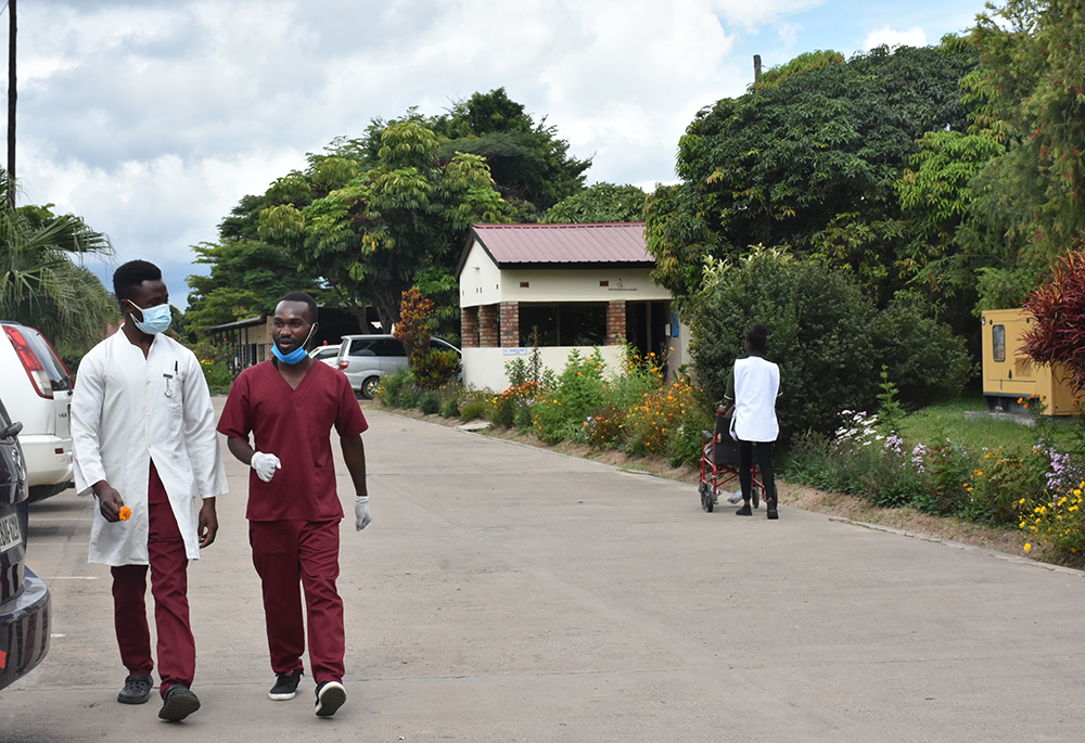 Health care attendants and one of the patients admitted at the health center walk outside at Our Lady's Health Centre in Kalingalinga. (GSR photo/Derrick Silimina)