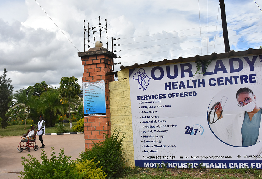 A health care attendant walks with one of the patients admitted at the health center in Kalingalinga. (GSR photo/Derrick Silimina)