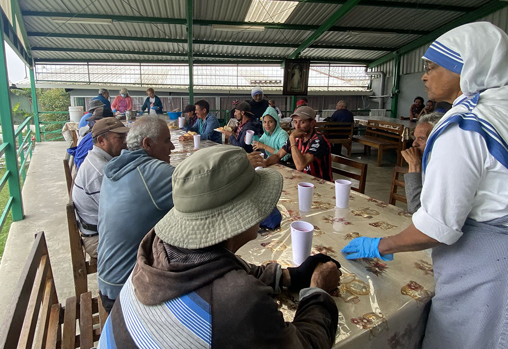 Personas sin hogar, entre ellas algunos migrantes, se sientan en un comedor para recibir comida de una hermana Misionera de la Caridad, el 1 de abril de 2023, en Coronado, Costa Rica.