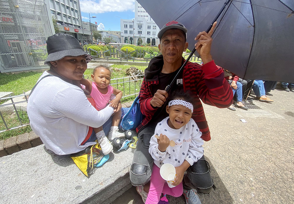 Elquin Lozano protege del sol a una de sus hijas con una sombrilla el 31 de marzo en el centro de San José, Costa Rica. El migrante colombiano y su familia pasaron por la peligrosa selva del Darién buscando un mejor futuro económico en otro país. 
