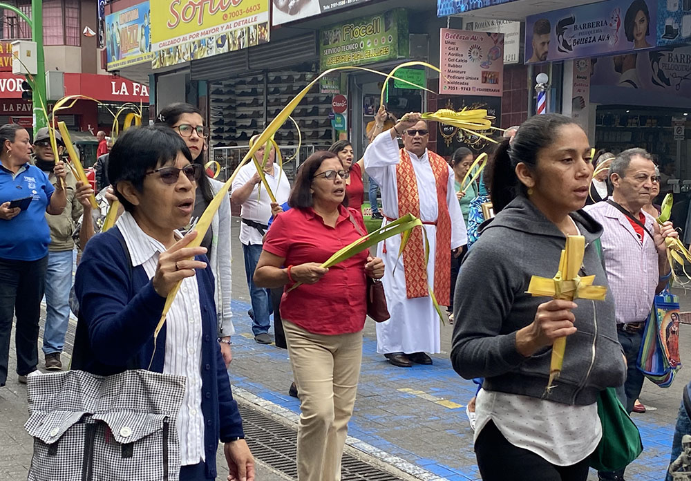 La hermana Scalabriniana María Angélica Tiralle, con suéter azul a la izquierda, participa en el Domingo de Ramos junto con migrantes de la Iglesia de Nuestra Señora de La Merced en San José, Costa Rica, el 2 de abril.